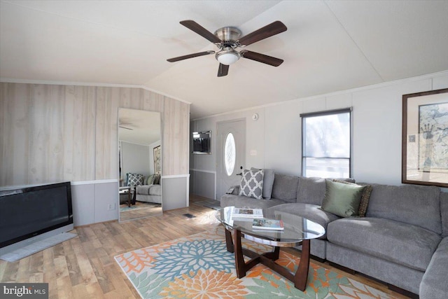 living area with ceiling fan, ornamental molding, vaulted ceiling, and wood finished floors