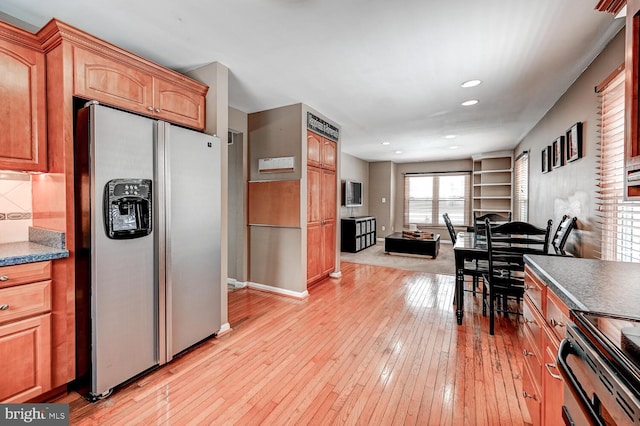 kitchen with electric stove, dark countertops, light wood-style floors, open floor plan, and stainless steel fridge