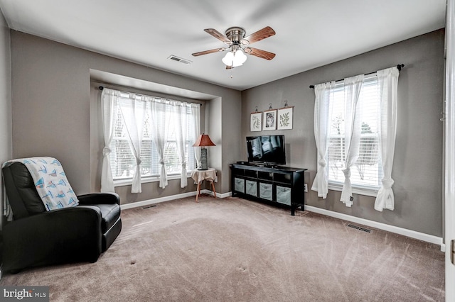 living area featuring a ceiling fan, carpet flooring, visible vents, and baseboards