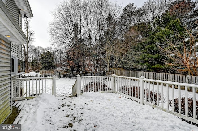 snowy yard featuring a fenced backyard and a deck