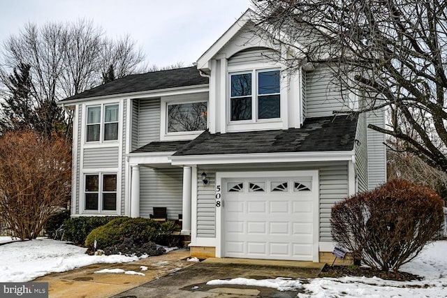 traditional-style house with a garage and a shingled roof