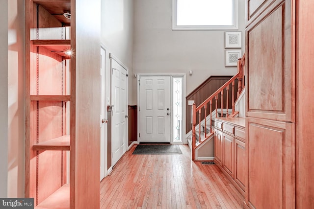 entryway with a high ceiling, stairway, and light wood-style floors