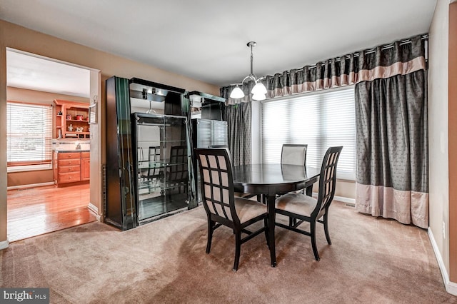 dining space featuring light carpet, baseboards, and a chandelier