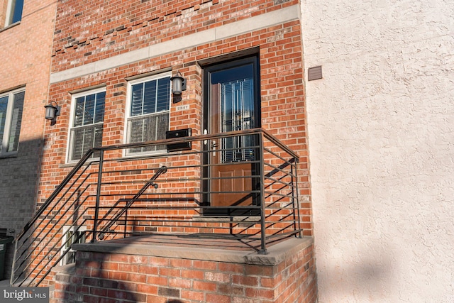 doorway to property with brick siding and stucco siding