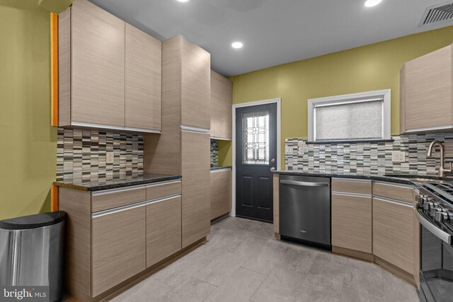 kitchen with stainless steel appliances, a sink, visible vents, decorative backsplash, and dark stone counters