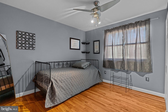 bedroom featuring ceiling fan, baseboards, and wood finished floors