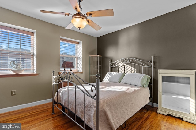 bedroom with a ceiling fan, baseboards, and wood finished floors