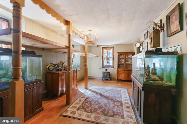 interior space with light wood-style floors, a baseboard heating unit, and a chandelier