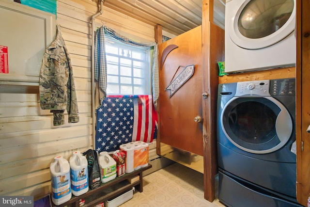 washroom featuring laundry area, stacked washer and clothes dryer, and wood walls