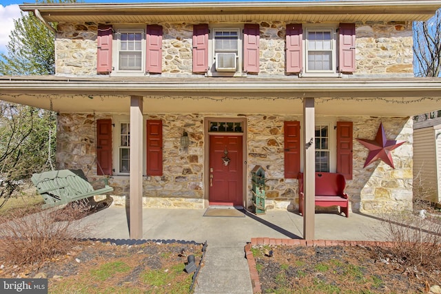 view of front of house featuring stone siding and a porch