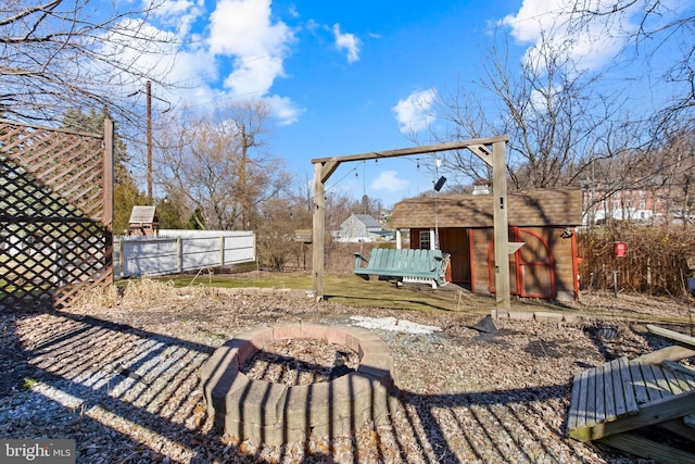 view of yard with an outdoor fire pit, fence, a wooden deck, and an outdoor structure