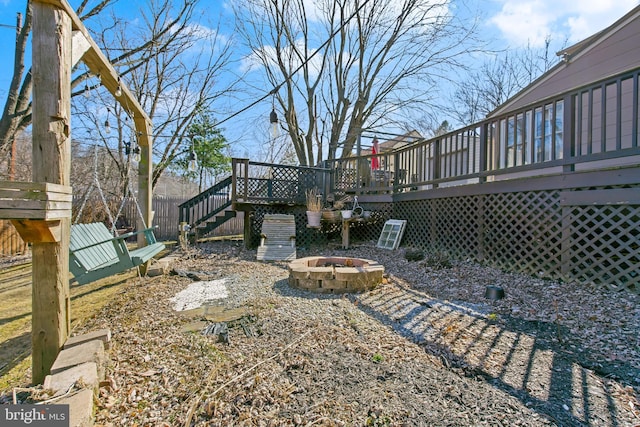 view of yard featuring stairs, a fire pit, fence, and a wooden deck