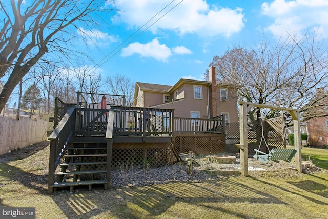 back of property featuring a chimney, a lawn, stairway, fence, and a deck