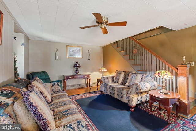 living area featuring stairway, a ceiling fan, a baseboard heating unit, and wood finished floors