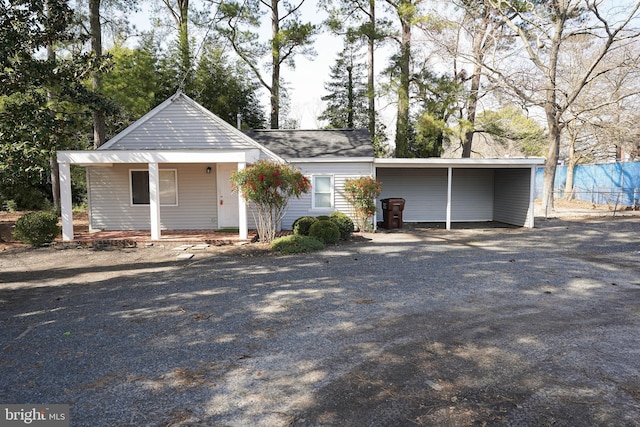 exterior space featuring gravel driveway, a porch, and a carport