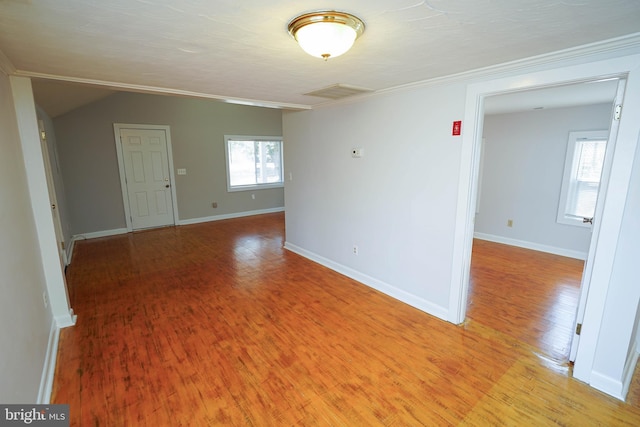 empty room featuring light wood-type flooring, baseboards, and lofted ceiling