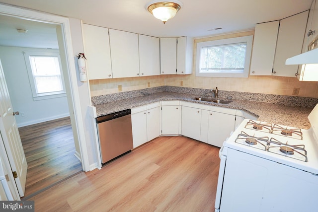 kitchen with white gas stove, a sink, stainless steel dishwasher, light wood-type flooring, and decorative backsplash