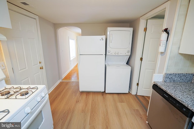 clothes washing area with visible vents, stacked washer and dryer, light wood-style flooring, and laundry area