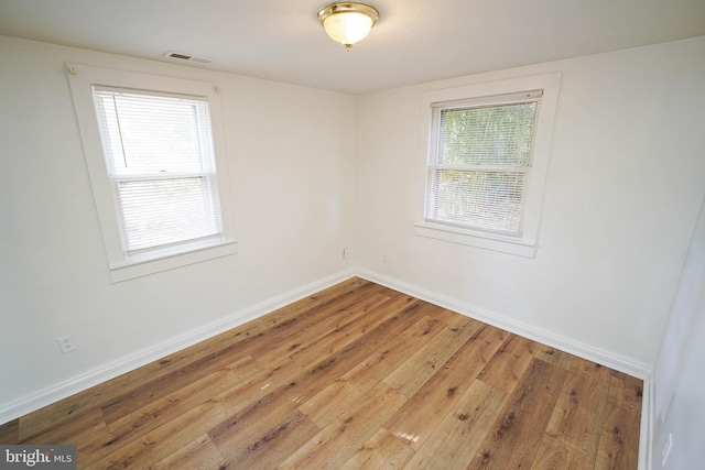 unfurnished room featuring wood finished floors, visible vents, and baseboards