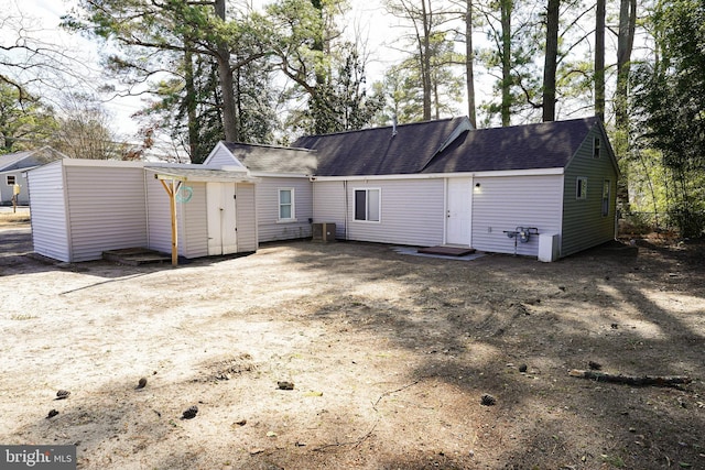 back of house featuring a shingled roof and central AC unit