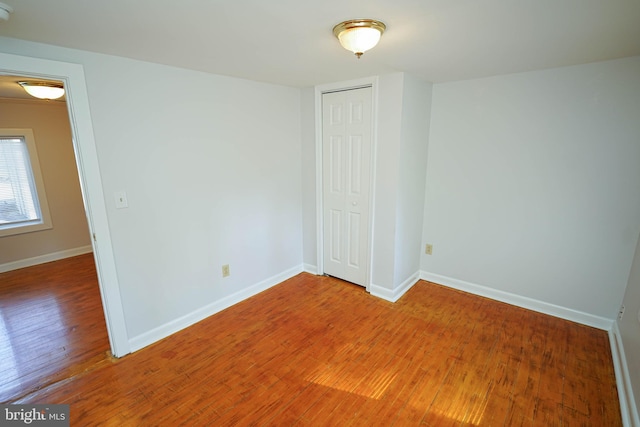 unfurnished bedroom with a closet, wood finished floors, and baseboards