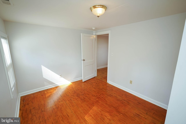 unfurnished room featuring baseboards, visible vents, and wood finished floors