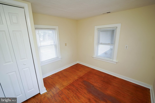 unfurnished room with dark wood-style floors, visible vents, and baseboards