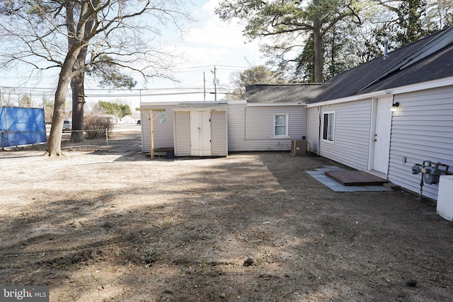 back of house featuring a shingled roof and fence