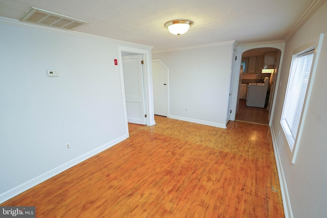 unfurnished room featuring visible vents, arched walkways, baseboards, light wood-style flooring, and ornamental molding