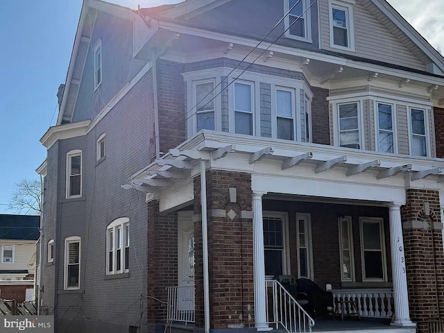 view of side of property with covered porch and brick siding