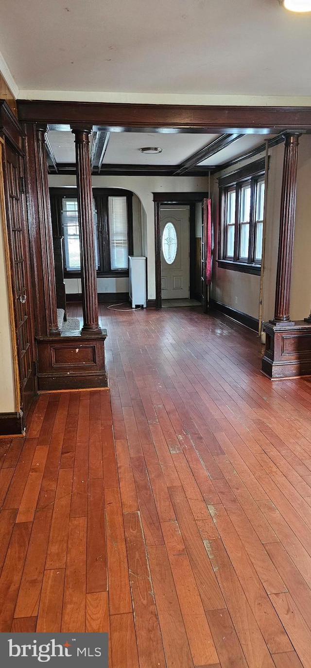 unfurnished living room with ornate columns, wood-type flooring, and baseboards