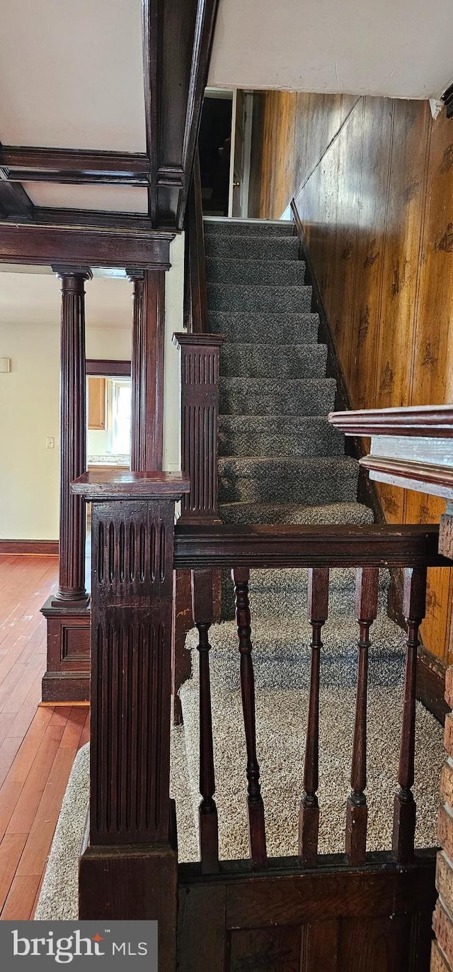 stairway featuring baseboards, decorative columns, and hardwood / wood-style floors