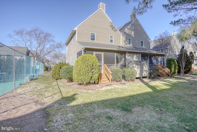 rear view of house with a yard, a chimney, and a sunroom