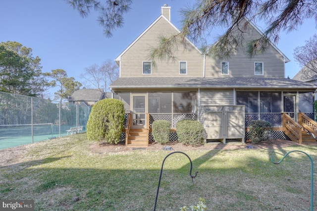 rear view of property with a tennis court, fence, a yard, and a sunroom