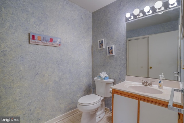 half bathroom with wallpapered walls, tile patterned floors, toilet, and vanity