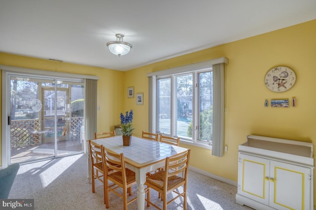 dining area with baseboards and light carpet