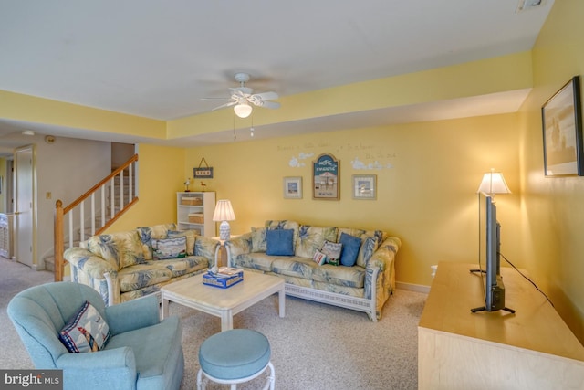 living room with baseboards, carpet floors, a ceiling fan, and stairs