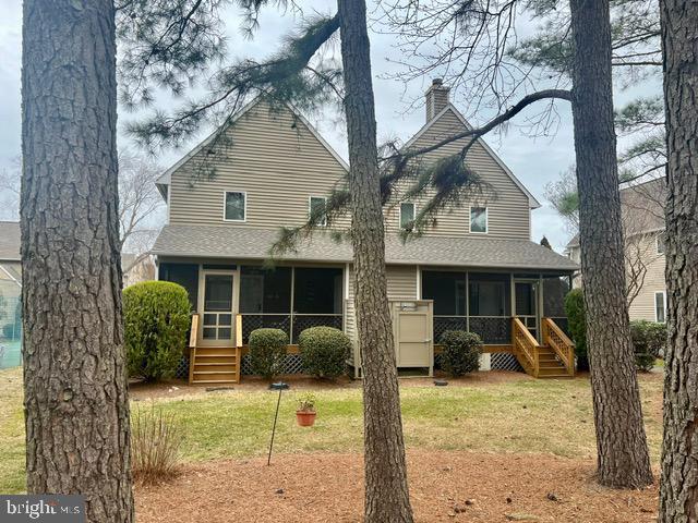 back of property featuring a chimney, roof with shingles, a yard, and a sunroom