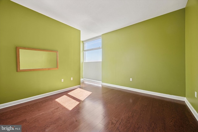 spare room featuring wood finished floors and baseboards