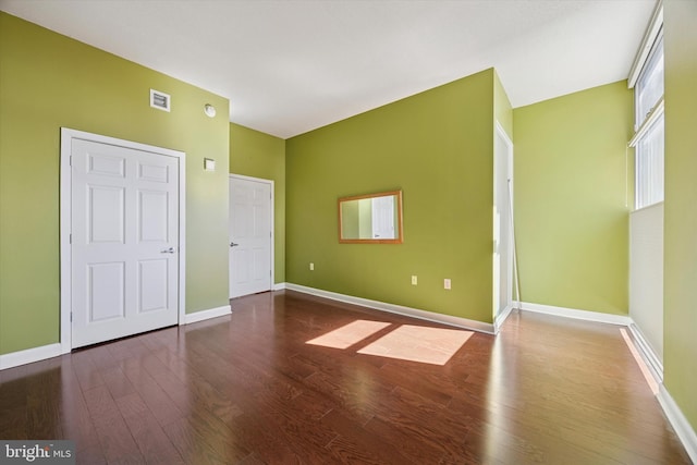 unfurnished bedroom featuring baseboards, visible vents, and wood finished floors