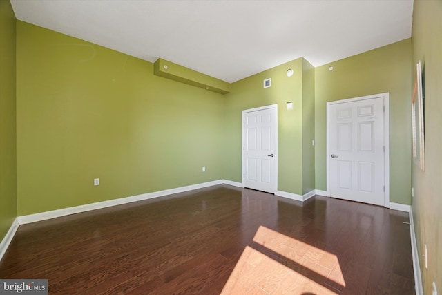 empty room featuring visible vents, baseboards, and wood finished floors