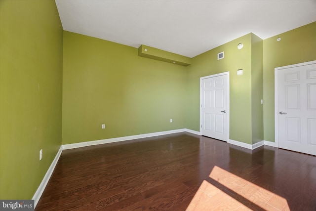 unfurnished room with visible vents, baseboards, and wood finished floors