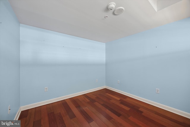 empty room featuring dark wood-style floors and baseboards