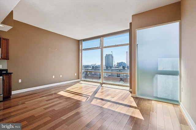 living area featuring a view of city, light wood finished floors, baseboards, and floor to ceiling windows