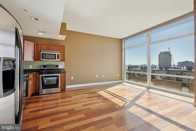 kitchen featuring a city view, stainless steel appliances, brown cabinets, light wood finished floors, and dark countertops