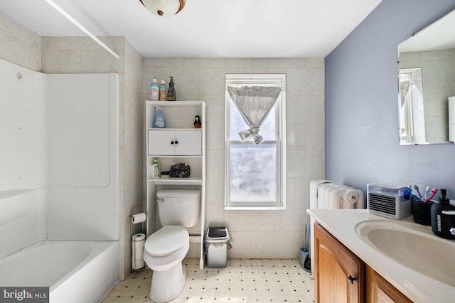 bathroom featuring plenty of natural light, vanity, toilet, and tile walls