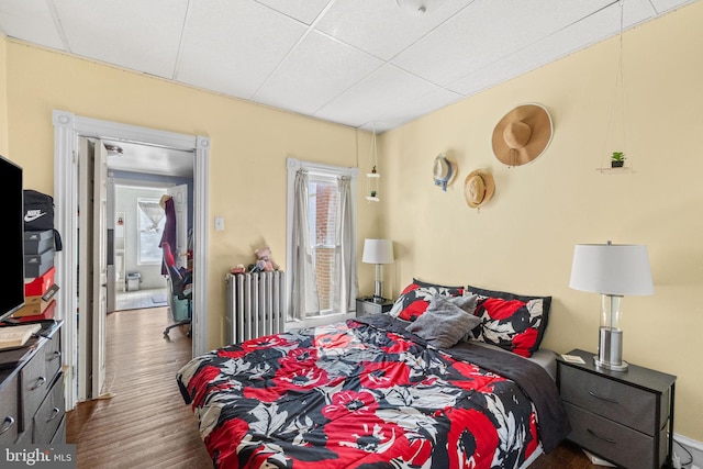 bedroom with radiator heating unit and wood finished floors