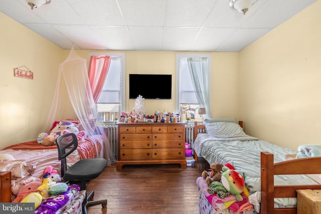 bedroom with multiple windows, wood-type flooring, and a paneled ceiling