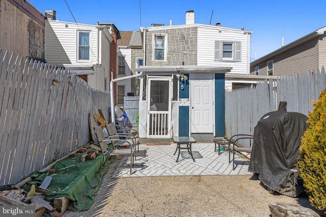 rear view of property featuring a fenced backyard and a patio