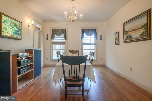 dining area featuring a chandelier, baseboards, and wood finished floors